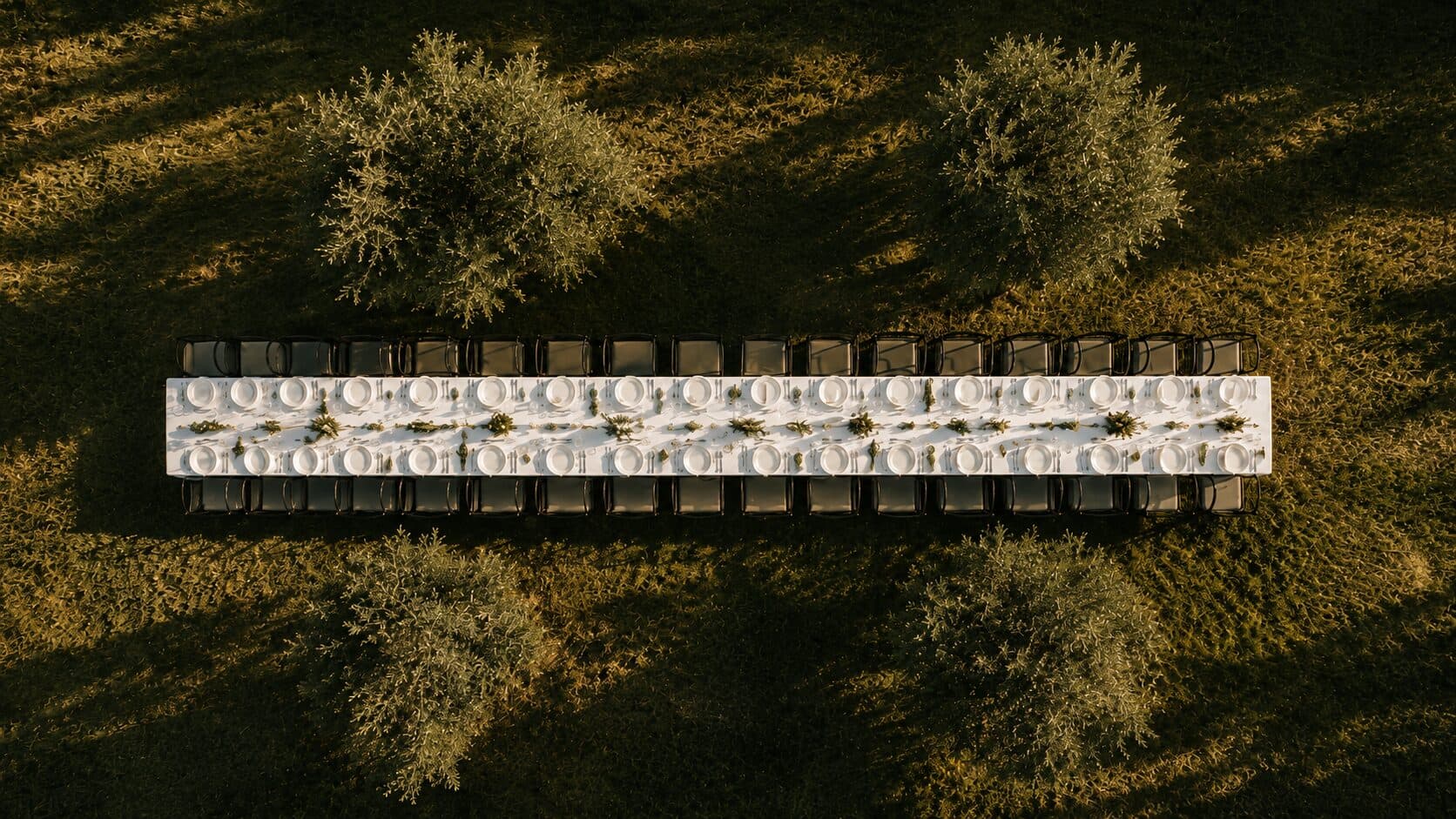 An intimate fine-dining table set against a vineyard hillside at dusk.