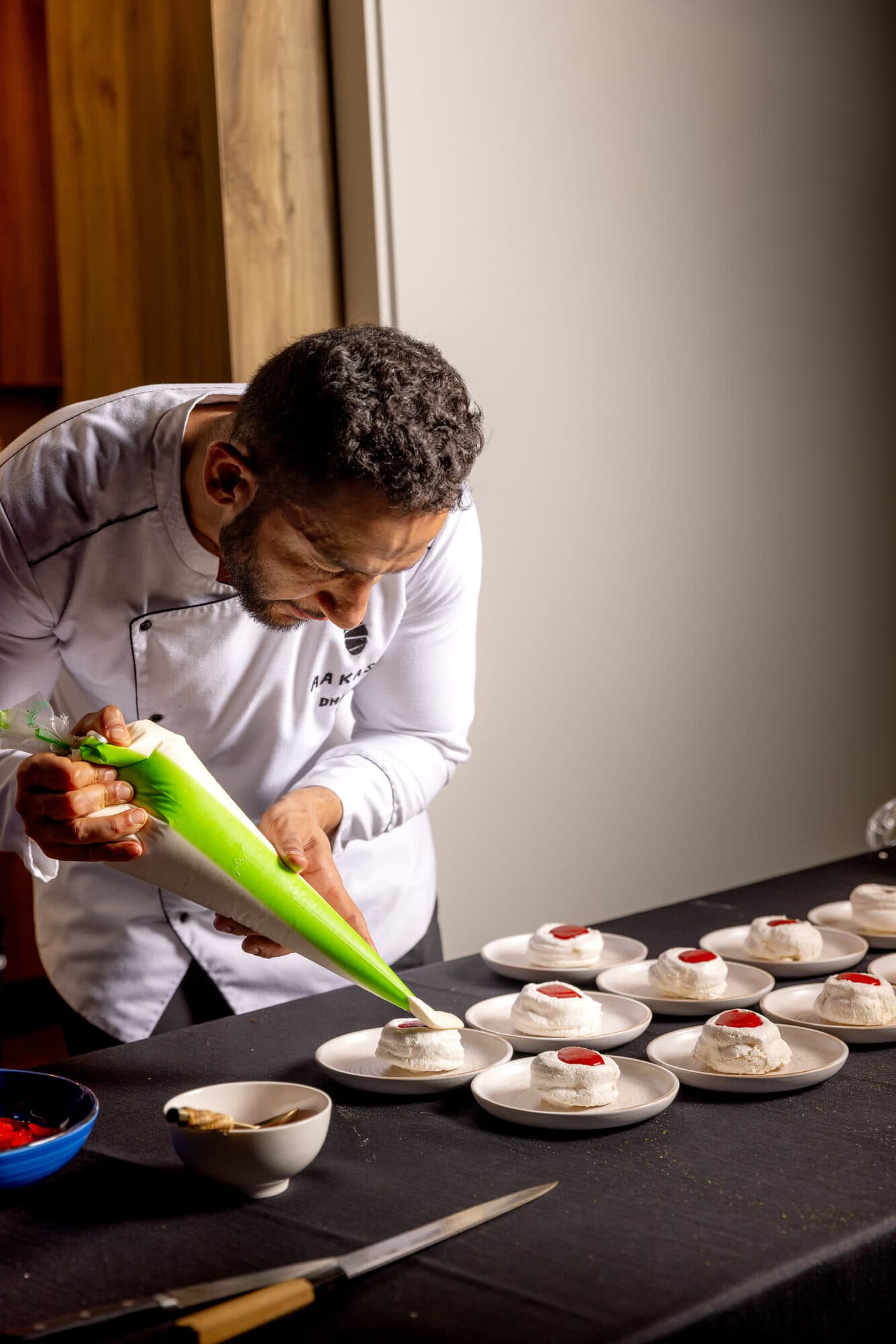 Chef Aakash piping a dessert component onto individual plates.
